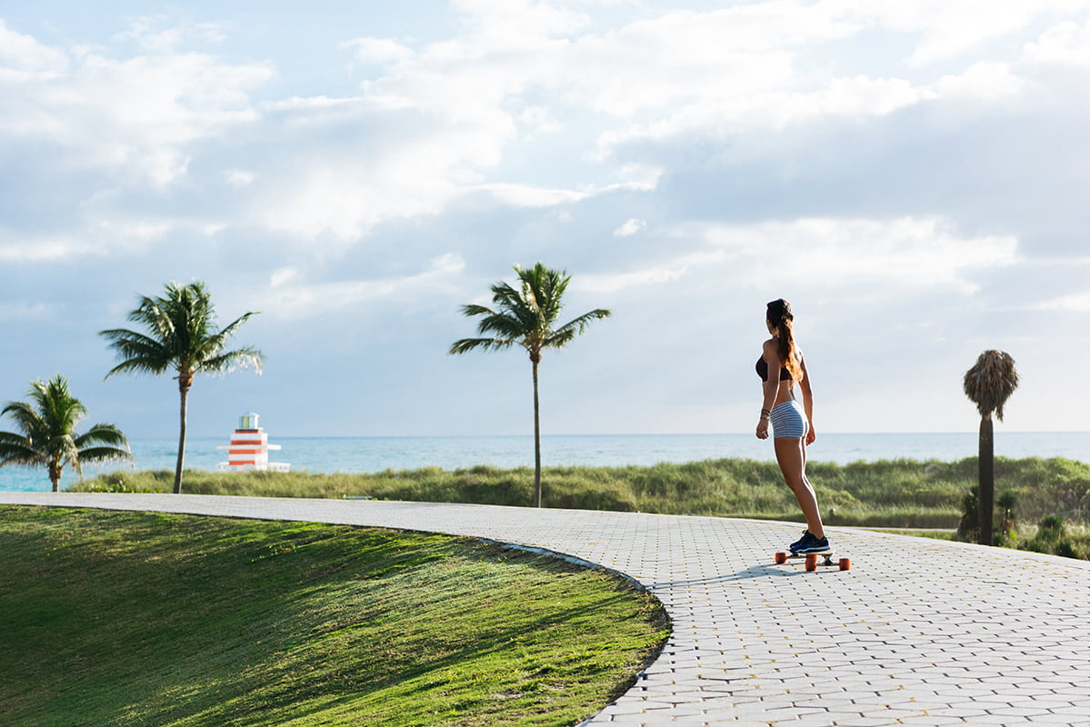 Femme sur un skateboard dans une allée près de la plage